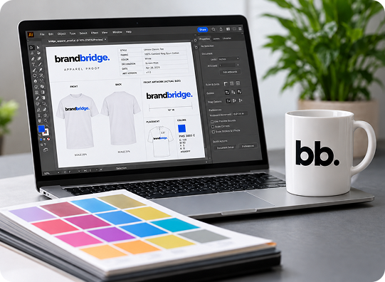 Brand Bridge apparel artwork on a laptop beside a colour swatch book